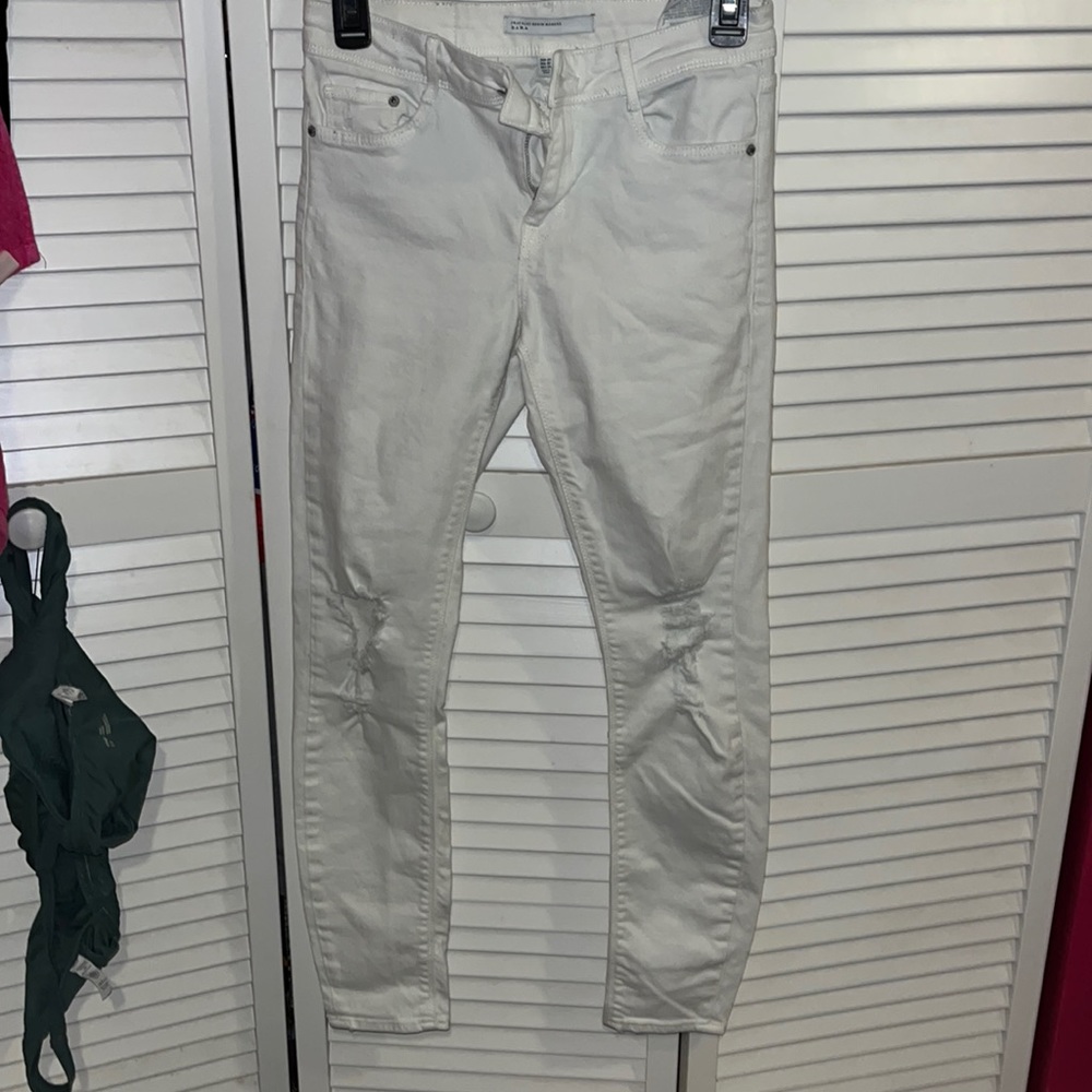 mid rise white jeans. rips at knees